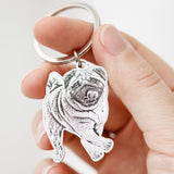 Silver custom dog photo keychain engraved with a pug, held in a hand